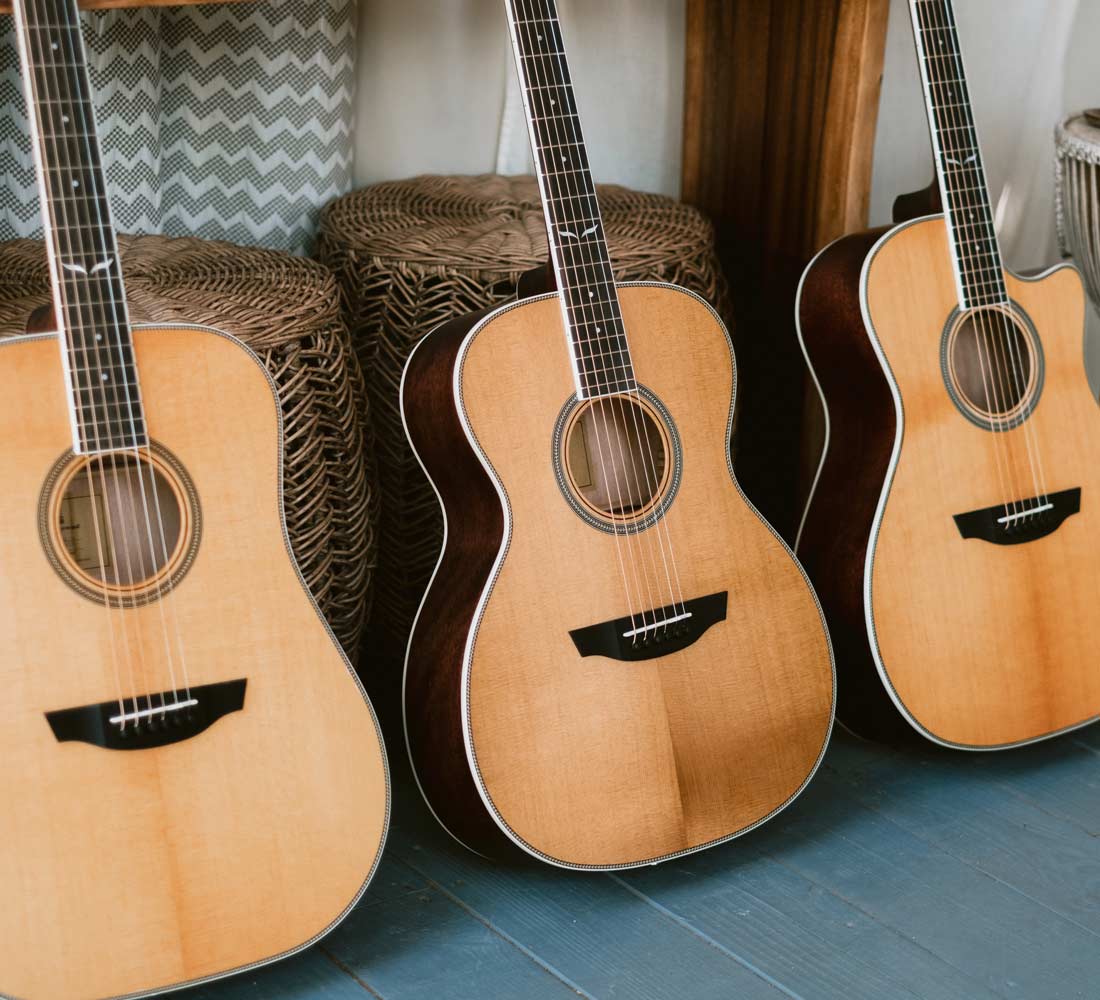 Three Orangewood guitars on blue wood floor