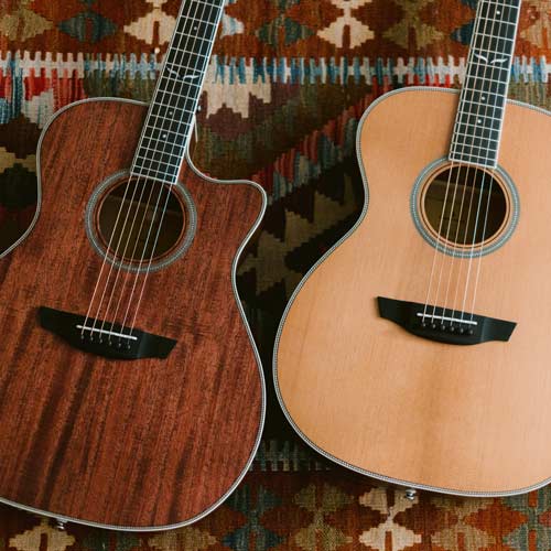 Two Orangewood Highland guitars lay on a tribal-patterned red orange rug