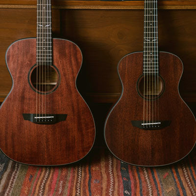 Two mahogany Orangewood Overland guitars lean against a wood dresser