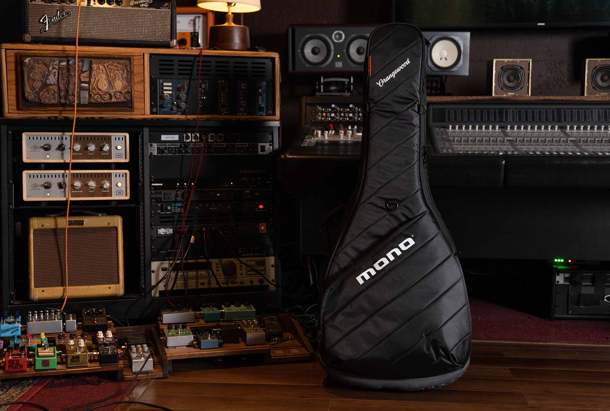 Mono Vertigo guitar case with orangewood logo in front of a recording studio soundboard