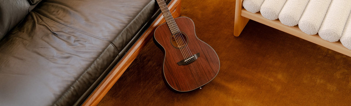 Mahogany guitar leaning on a black sofa