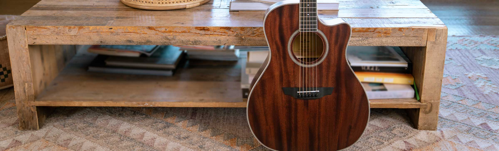 The Ava Torrefied Spruce guitar resting on a brown leather couch.