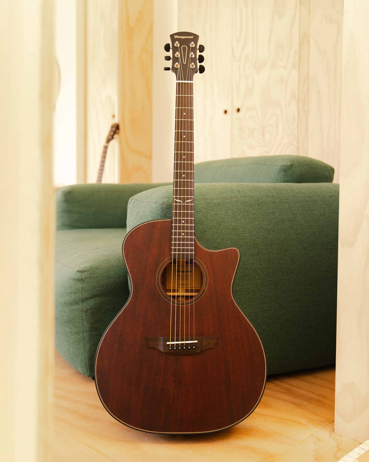 Morgan mahogany guitar against a green sofa