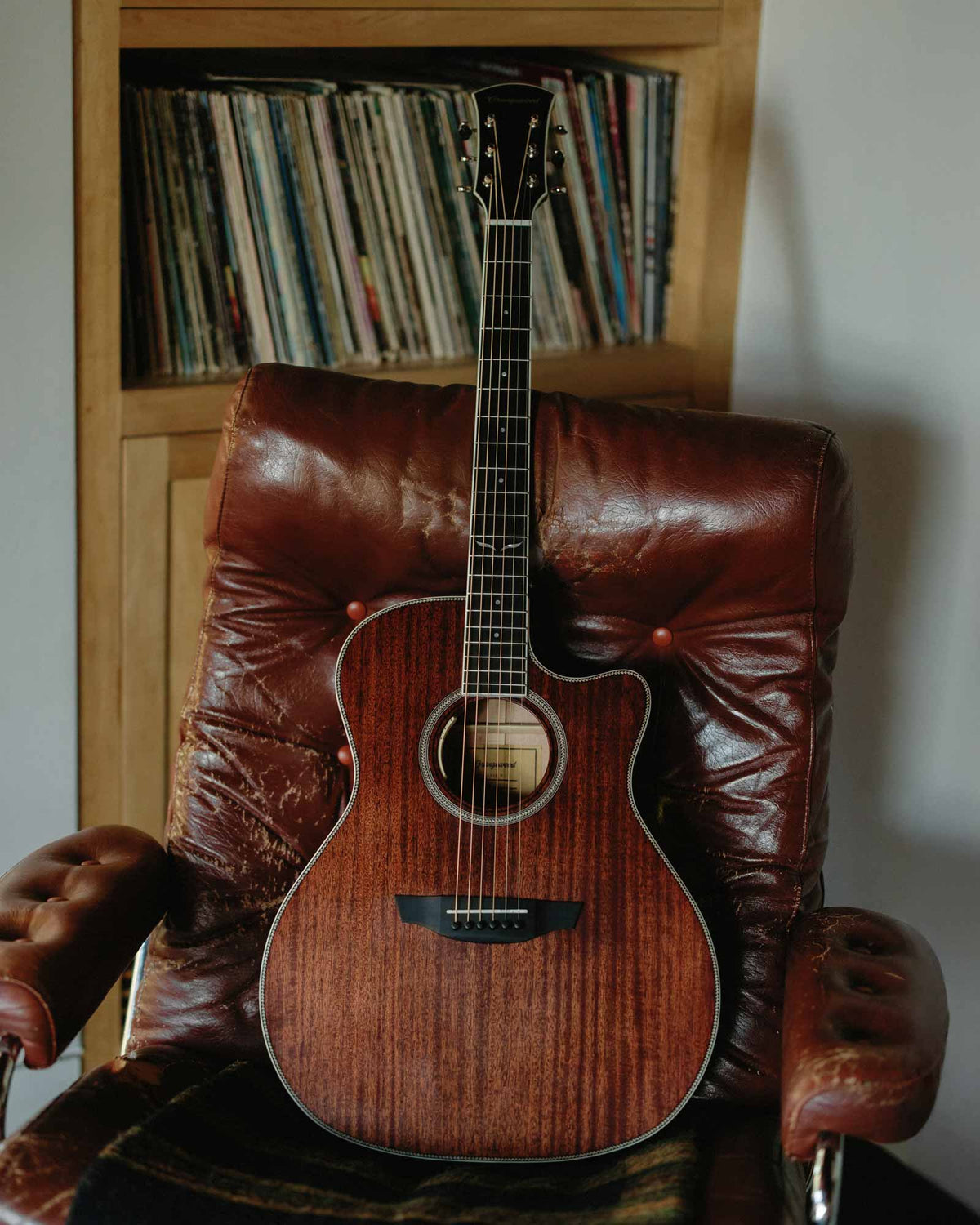 Sage mahogany live guitar on a leather chair