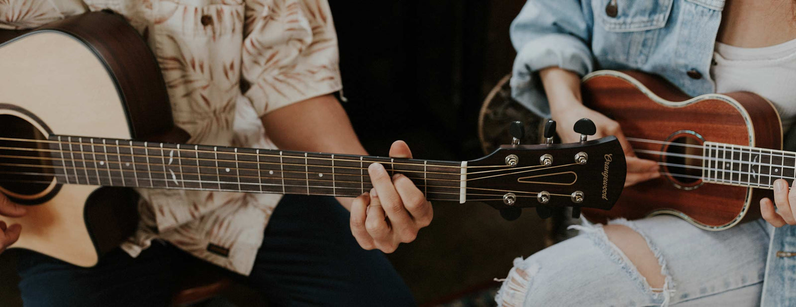 Two people play an Orangewood guitar and ukulele next to each other