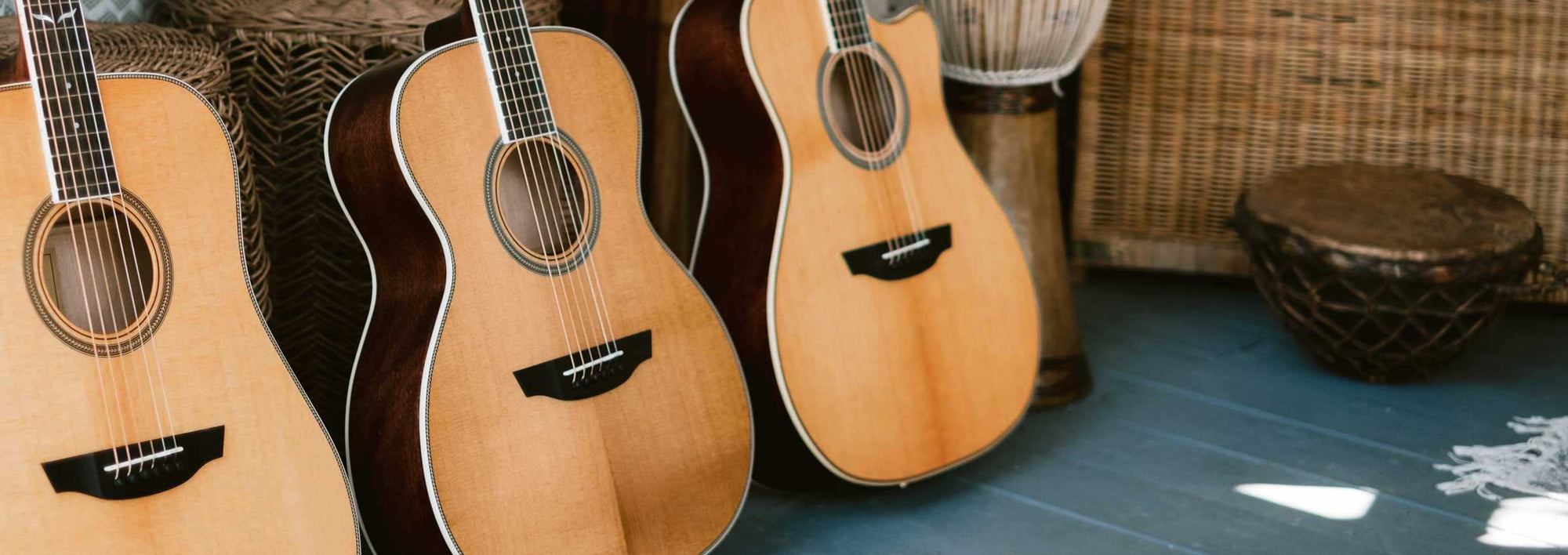 Three Orangewood guitars on a blue wood floor