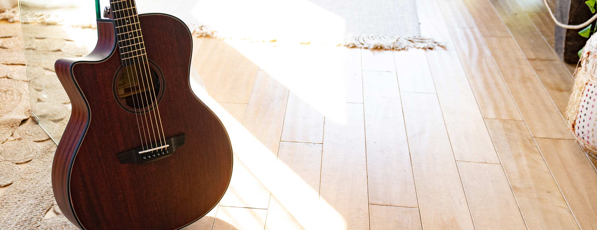A left-handed Orangewood Morgan Mahogany guitar on light wood floor