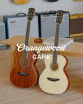 Orangewood Care: mahogany and white acoustic guitars in a room with amplifiers
