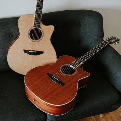 Two Orangewood Playa guitars lay on a teal couch